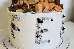 Vanilla cake with Vanilla buttercream and villa cookies in between layers. Adorned with lots of yummy sweets on top. And letter shaped sprinkles.